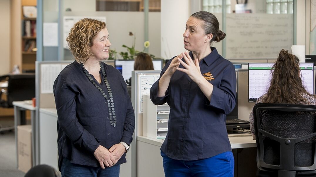 Two colleagues communicate in Auslan in an office.