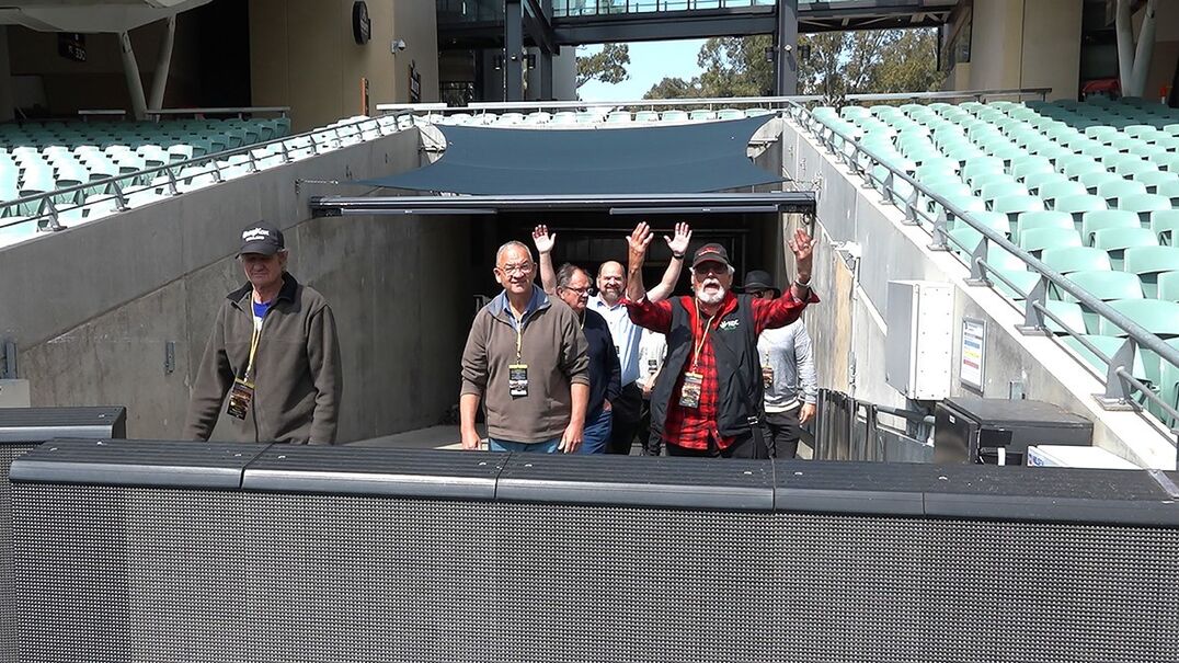 A group of deaf men applaud at a stadium